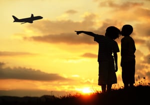 Two kids silhouette on meadow looking at airplane in air-1